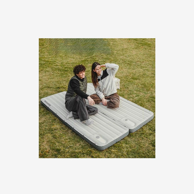 Two campers resting on connected Naturehike air mattresses inside a tent