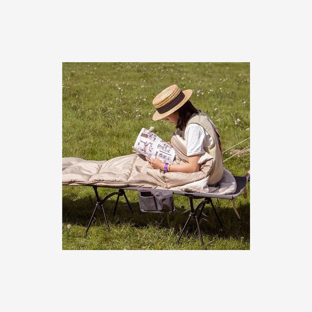 Camper relaxing on grass inside a Naturehike E200 cotton sleeping bag