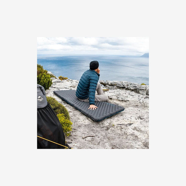 Backpacker relaxing on R3.5 pad next to campfire in chilly mountain terrain