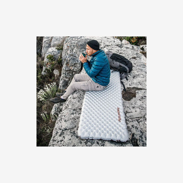 Camper resting on R5.8 envelope sleeping pad in forest setting