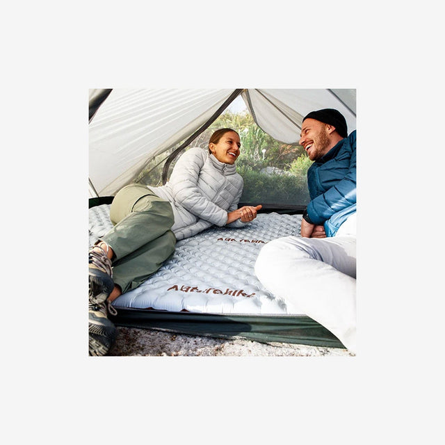 Camper resting on R5.8 envelope sleeping pad in forest setting