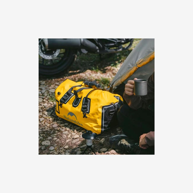 Camper carrying rugged duffel dry bag across rocky terrain