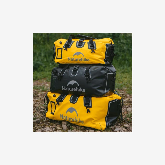 Camper carrying rugged duffel dry bag across rocky terrain