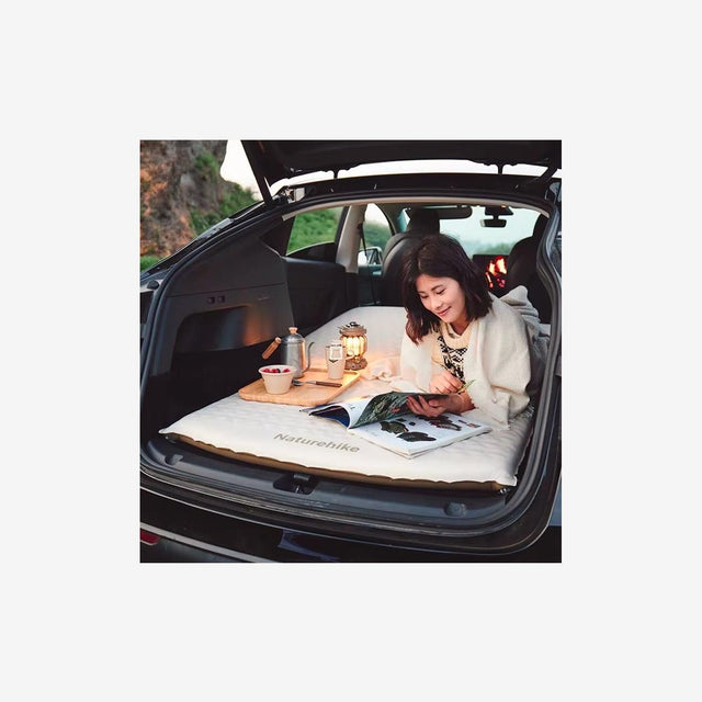Camper relaxing on inflated bed inside vehicle during a road trip