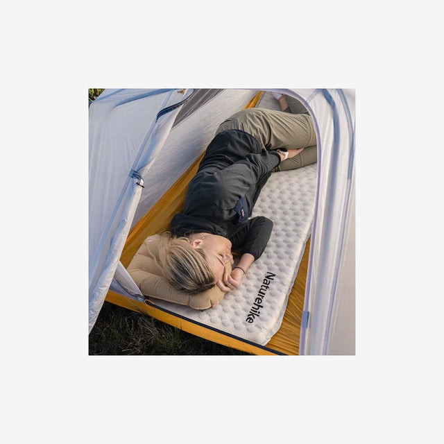 backpacker resting on Fish Bone pad under a lightweight tarp shelter