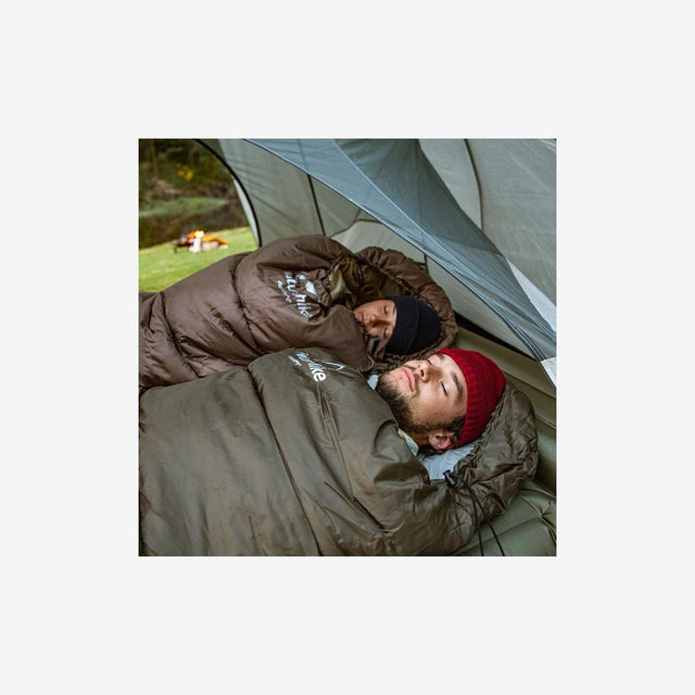 Camper resting comfortably inside Naturehike U Series sleeping bag outdoors