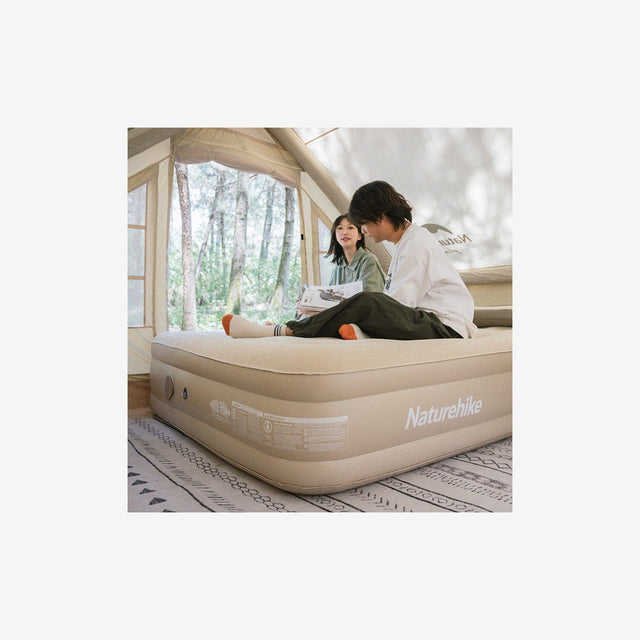 Camper inflating PVC airbed inside tent during camping trip