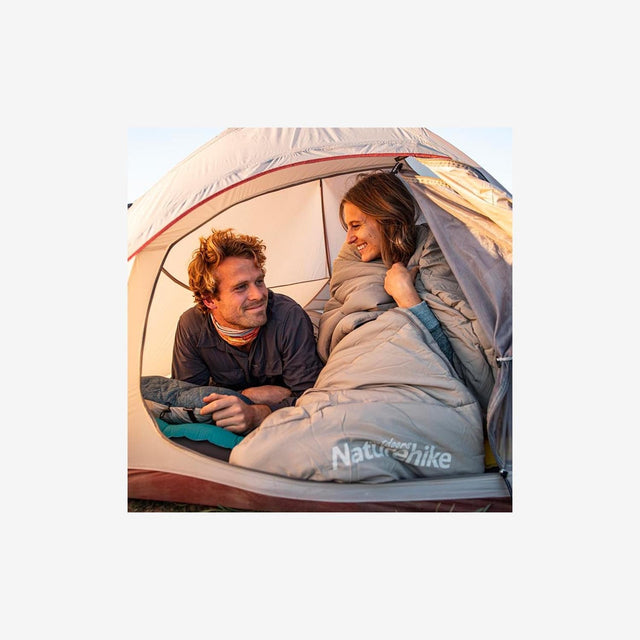 Camper relaxing beside a tent using a washable sleeping bag in mild conditions