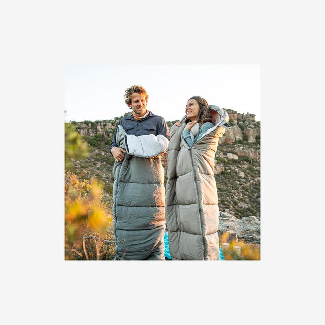 Camper relaxing beside a tent using a washable sleeping bag in mild conditions